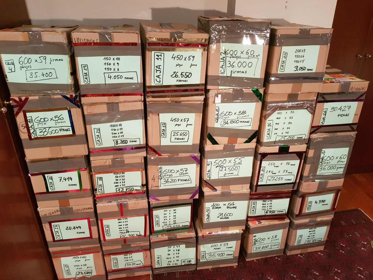 Decenas de cajas de cartón apiladas y etiquetadas a mano con el número de pliegos y firmas que contiene cada una